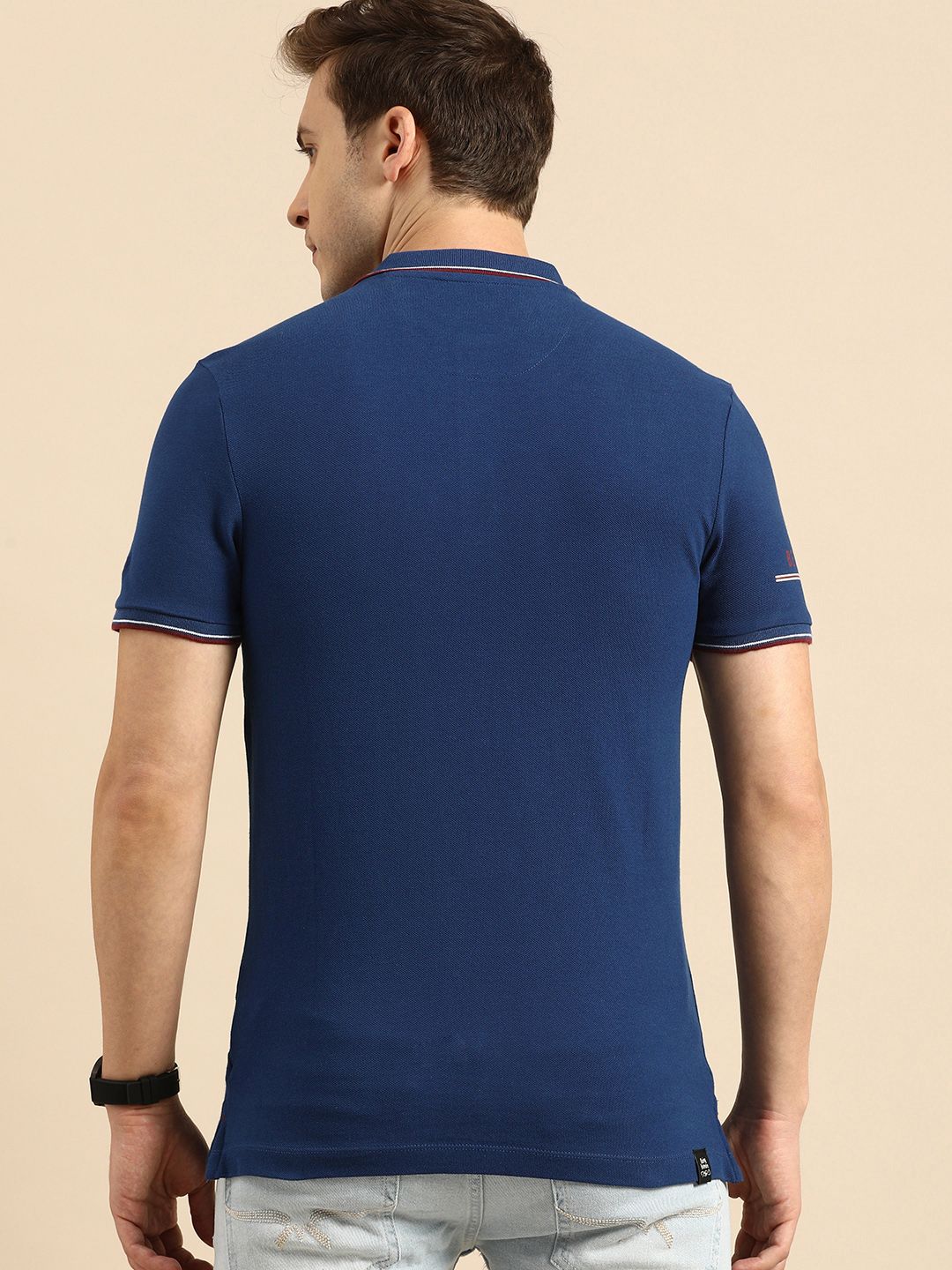 Menjadi T-shirt kolar polo biru manusia dengan perincian bercetak