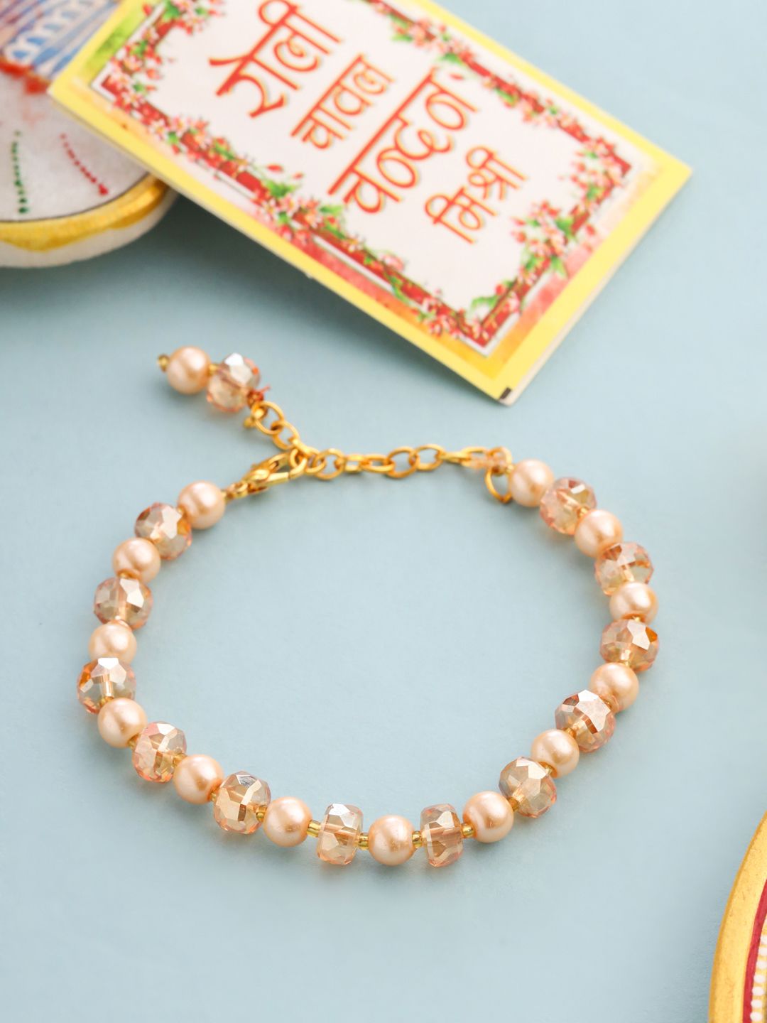 NVR Women Gold Toned Artificial Beads Wraparound Rakhi with Roli Chawal Chandan & Mishri